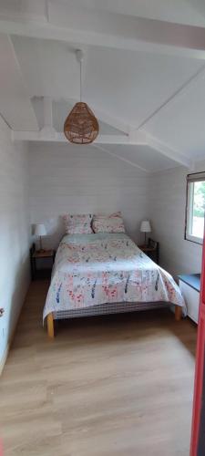 une chambre avec un lit avec une couette fleurie dans l'établissement Charmant Chalet -La Lande - 4 pers-24h du Mans, à Cérans-Foulletourte