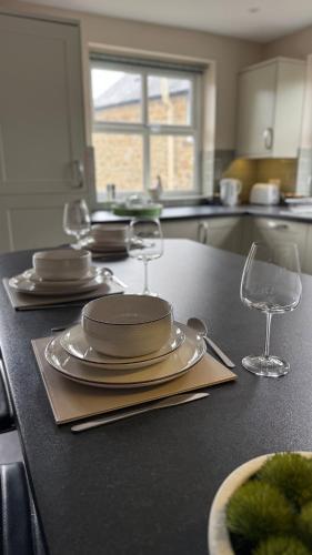a kitchen with plates and wine glasses on a counter at Wisteria Cottage in Eyam