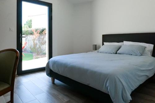 ein Schlafzimmer mit einem Bett und einem großen Fenster in der Unterkunft Villa des Hérondais avec piscine - idéal familles - 8 personnes in Jard-sur-Mer