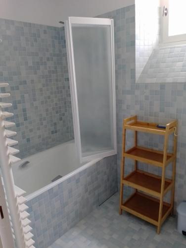une salle de bain avec une douche et une baignoire et une étagère dans l'établissement Charmante maison de centre bourg avec jardin, à Saint-Sozy
