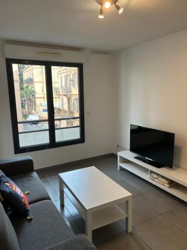 un salon avec un canapé, une télévision et une table dans l'établissement studio confortable, à Cannes