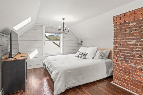 a bedroom with a bed and a brick wall at Stunning Heritage Home, Sleep 10, Hot Tub, Private Yard, Firepit, in Vernon