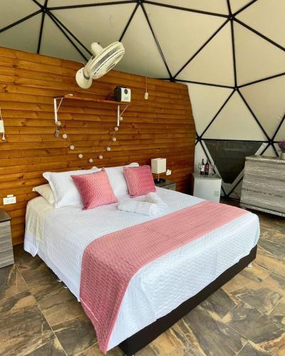 a large bed with pink pillows in a room at Eco Boutique-Naranjo in La Vega