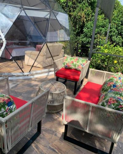 a patio with three chairs and a table and a chair with a red seat at Eco Boutique-Naranjo in La Vega