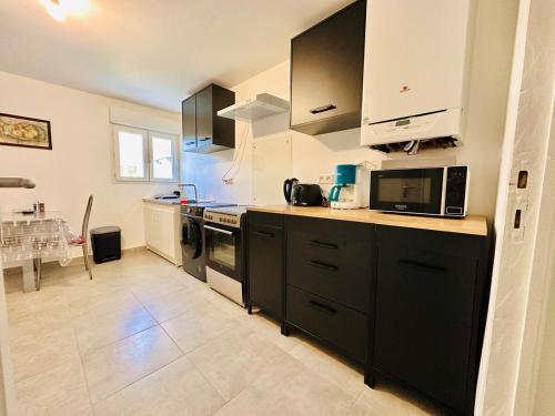 une cuisine avec des armoires noires et un four micro-ondes dans l'établissement L'Horizon de la cité, à Carcassonne