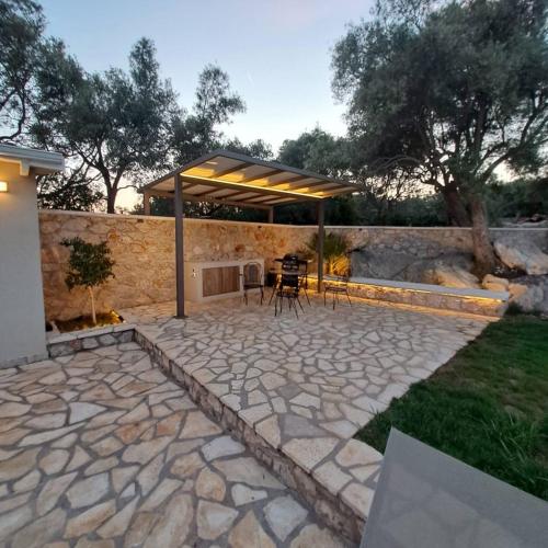 a stone patio with a pavilion in a backyard at Lefkolia Retreat in Sivota