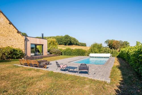 une arrière-cour avec une piscine entourée de chaises et une maison dans l'établissement Magnifique longère du Perche avec vue panoramique et piscine pour 9 personnes, à Le Gué-de-la-Chaîne