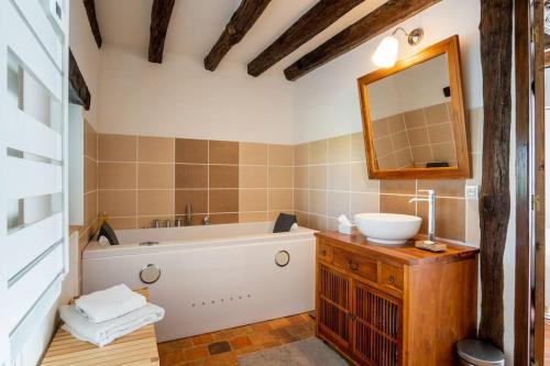 une salle de bain avec une baignoire, un lavabo et un miroir dans l'établissement Magnifique longère du Perche avec vue panoramique et piscine pour 9 personnes, à Le Gué-de-la-Chaîne