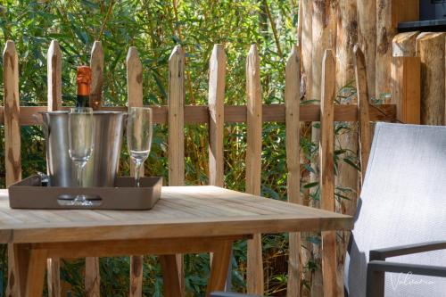 a wooden table with a wine glass and a bucket at Les Cabanes du Beau Vallon in Profondeville