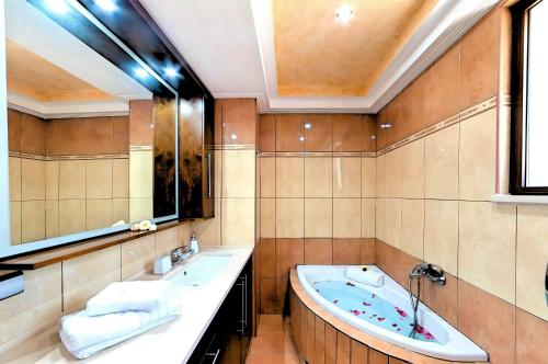 a bathroom with a tub and a sink and a mirror at Sunlight Villa Beheizter Pool in Georgioupolis