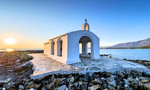 a small chapel on the shore of a body of water at Sunlight Villa Beheizter Pool in Georgioupolis