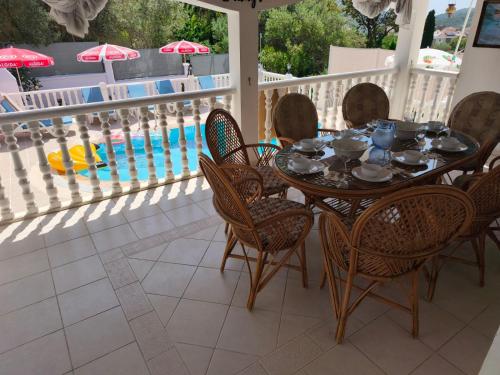 a table and chairs on a balcony with a pool at Villa Yelken Oludeniz in Ovacik