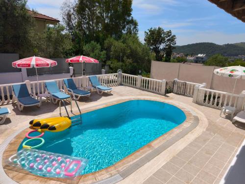 a small swimming pool with chairs and umbrellas at Villa Yelken Oludeniz in Ovacik