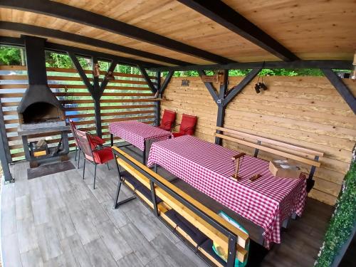 two tables and chairs on a deck with a fireplace at Vikendica Anas in Tuzla