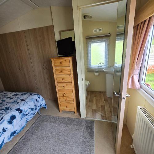 a bedroom with a bed and a sink and a mirror at Thornwick bay- xantus grange 60 in Flamborough
