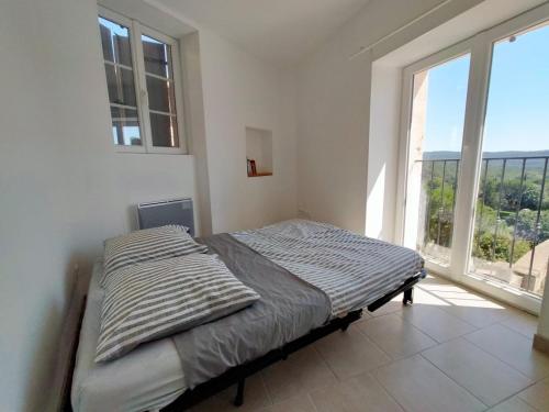 un lit dans une chambre avec une grande fenêtre dans l'établissement appartement avec terrasse et vue dégagée, à Villecroze
