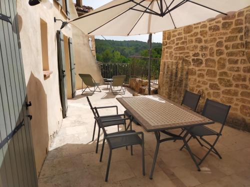 un patio avec une table, des chaises et un parasol dans l'établissement appartement avec terrasse et vue dégagée, à Villecroze