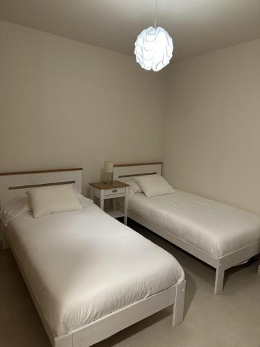 two beds in a room with a pendant light at Casita San Juan in Pilar de Jaravía