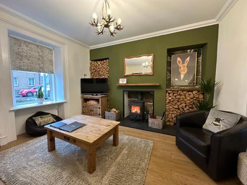 a living room with a table and a fireplace at Wells Street Cottages No 26 By The River Ness in Inverness