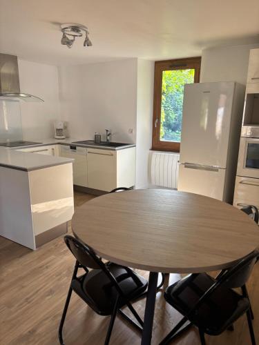 une cuisine avec une table, des chaises et un réfrigérateur dans l'établissement La Maison du Ruisseau, à Strenquels
