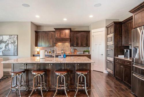 a kitchen with wooden cabinets and a island with bar stools at Luxury Stay with Golf Simulator and 3 King Bedrooms in Elkhorn