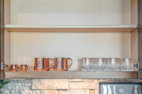 a row of copper mugs sitting on a shelf at Luxury Stay with Golf Simulator and 3 King Bedrooms in Elkhorn
