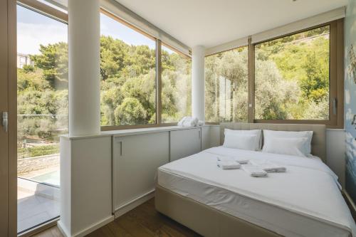 a bedroom with a bed and large windows at Villa Solaria in Sveti Stefan