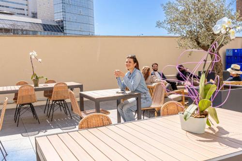 a woman sitting at a table on a patio at Novotel Suites Paris Montreuil Vincennes in Paris