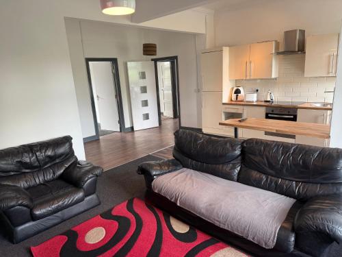 a living room with two leather couches and a kitchen at Lux spacious 3BR entire apartment in Wakefield
