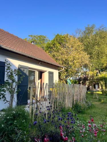 une maison avec une clôture et des fleurs dans la cour dans l'établissement Charmante maisonnette, à La Celle-sous-Gouzon