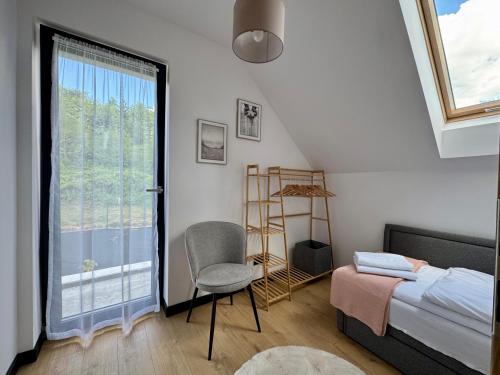 a bedroom with a bed and a chair and a window at Domek na Rybackiej in Swarzewo