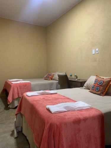 a room with two beds with red sheets at Refúgio Serra da Capivara 02 in Coronel José Dias