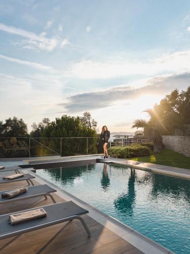 a woman is standing next to a swimming pool at Villa Solaria in Sveti Stefan