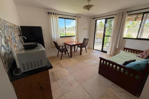 a living room with a bed and a tv and a table at Aldeias Guajiru Apart in Trairi