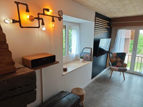 a living room with a radio and a chair and windows at Un Coin De Gîtes in Sciez