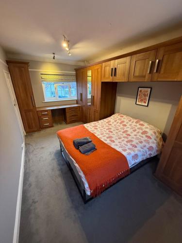 a bedroom with a bed with an orange blanket at Spacious 3 bed house garden & parking sleeps 5 in Belvedere