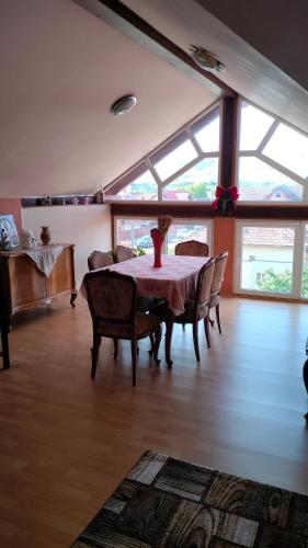 a dining room with a table and chairs and windows at Casa Emil in Floreşti