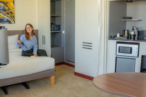 a woman sitting on a bed in a room at Novotel Suites Paris Montreuil Vincennes in Paris