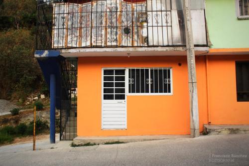 ein orangefarbenes Gebäude mit einem Balkon und einer weißen Tür in der Unterkunft Cozy family apartment, kitchen in Mineral del Monte
