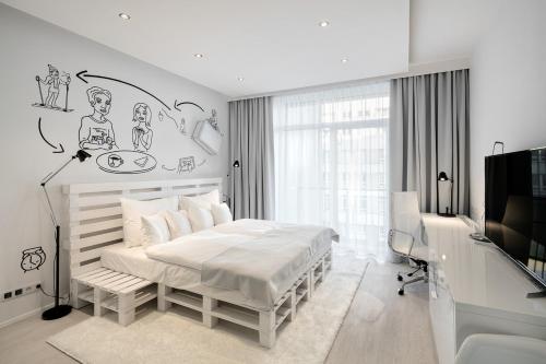 a white bedroom with a bed and a tv at Pytloun Grand Hotel Imperial in Liberec