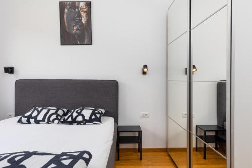 a bedroom with a black and white bed and a mirror at Modern Top Floor Sea View 3BR with Pools, Spa & Fitness in Becici