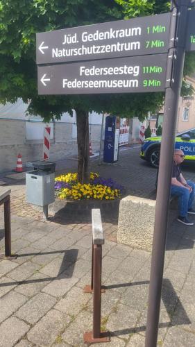 a street sign on a pole next to a bench at nJoy! Federsee Getaway - Central - Coffee - Balcony - perfect for business and travel in Bad Buchau