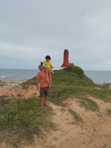 a man standing on a beach with two children on his shoulders at Chales Da Mata in Fortim