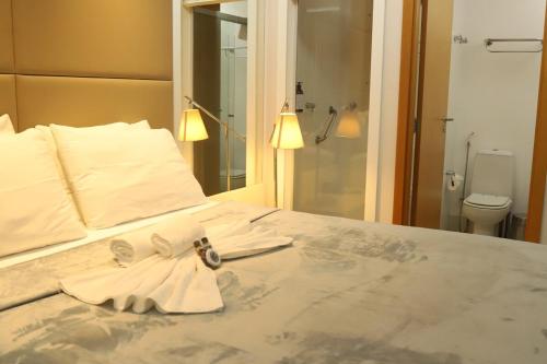 a bedroom with a bed with towels and a bathroom at Flat Hilton inn - Belo Horizonte 1005 in Belo Horizonte
