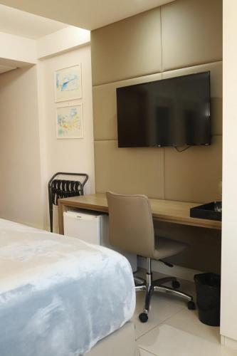a hotel room with a desk and a television at Flat Hilton inn - Belo Horizonte 1005 in Belo Horizonte