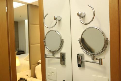 two mirrors hanging on a wall in a bathroom at Flat Hilton inn - Belo Horizonte 1005 in Belo Horizonte