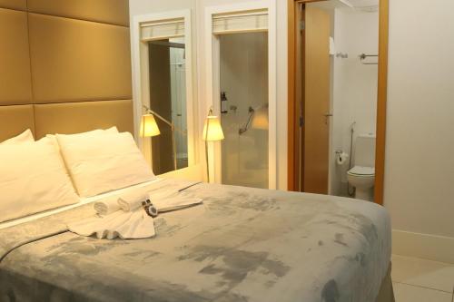 a bedroom with a bed and a bathroom with a toilet at Flat Hilton inn - Belo Horizonte 1005 in Belo Horizonte