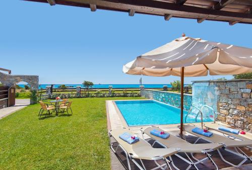 a villa with a swimming pool and an umbrella at Horizon Line Villas in Kiotari
