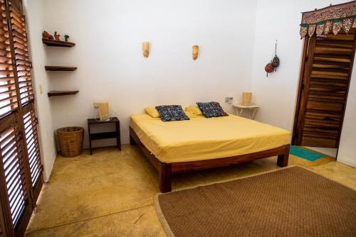 a bedroom with a bed with yellow sheets and blue pillows at Villa Lumina - Beachfront Escape Private Pool, Spacious & Serene in Paso Hondo