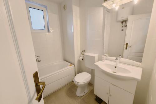 a white bathroom with a toilet and a sink at Apartment SeaView in Utjeha